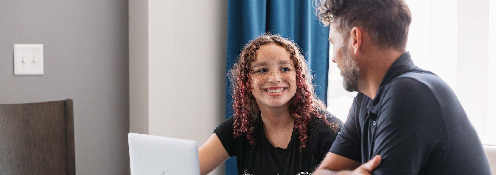 An adoptive dad sits at a table with his teen daughter